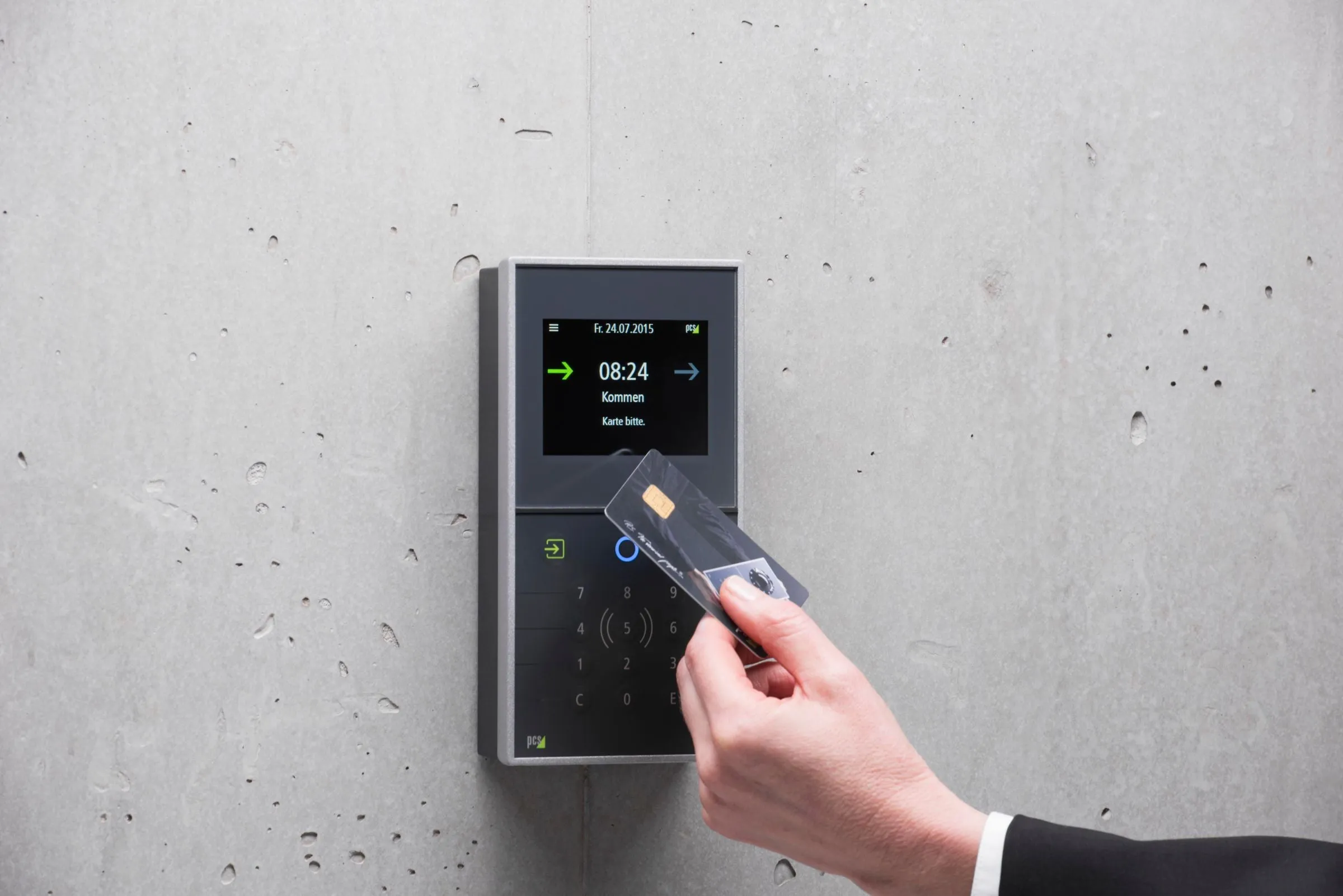 A hand presenting an access card to a reader on a concrete wall