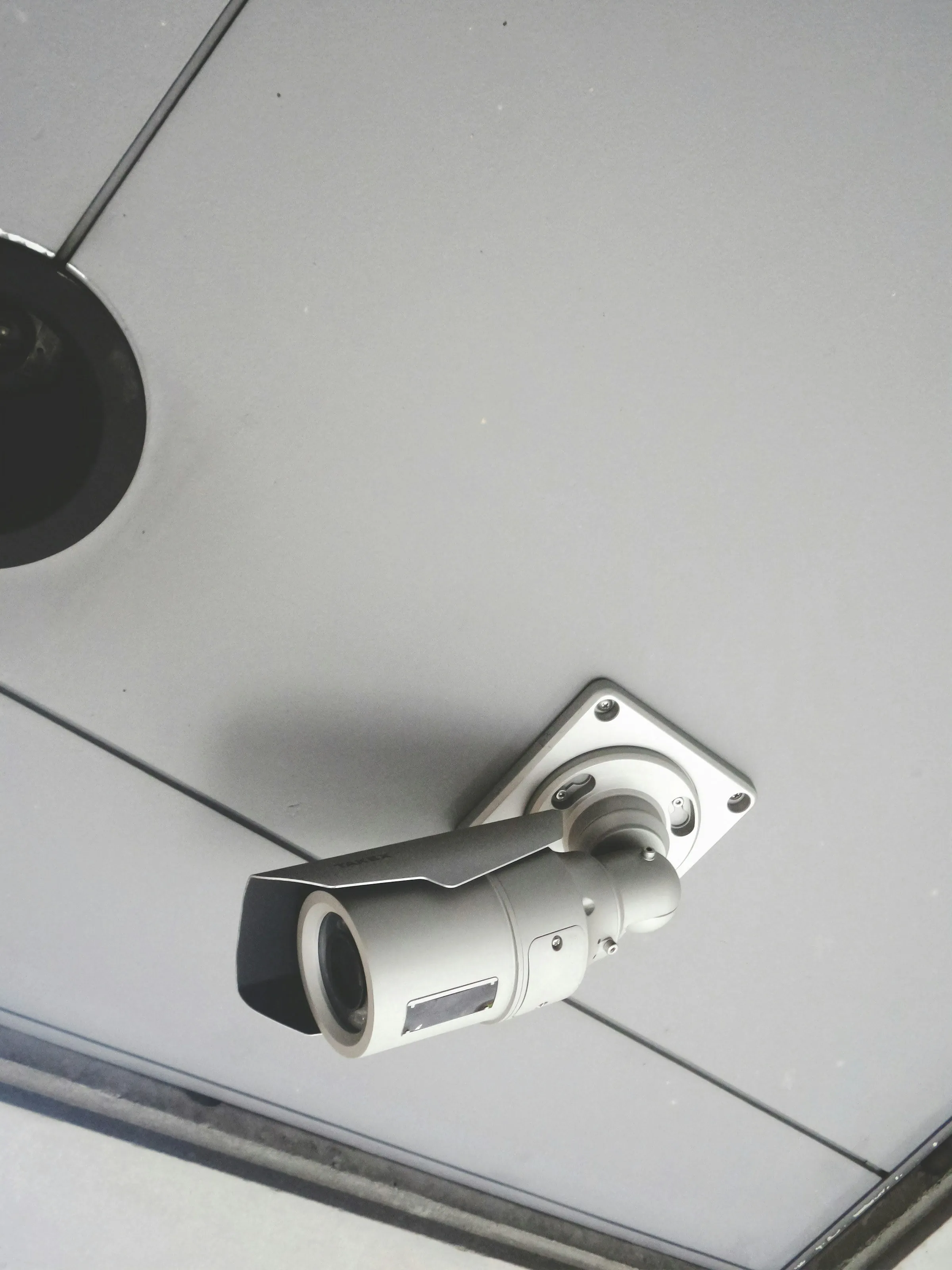 A white bullet security camera mounted on a ceiling