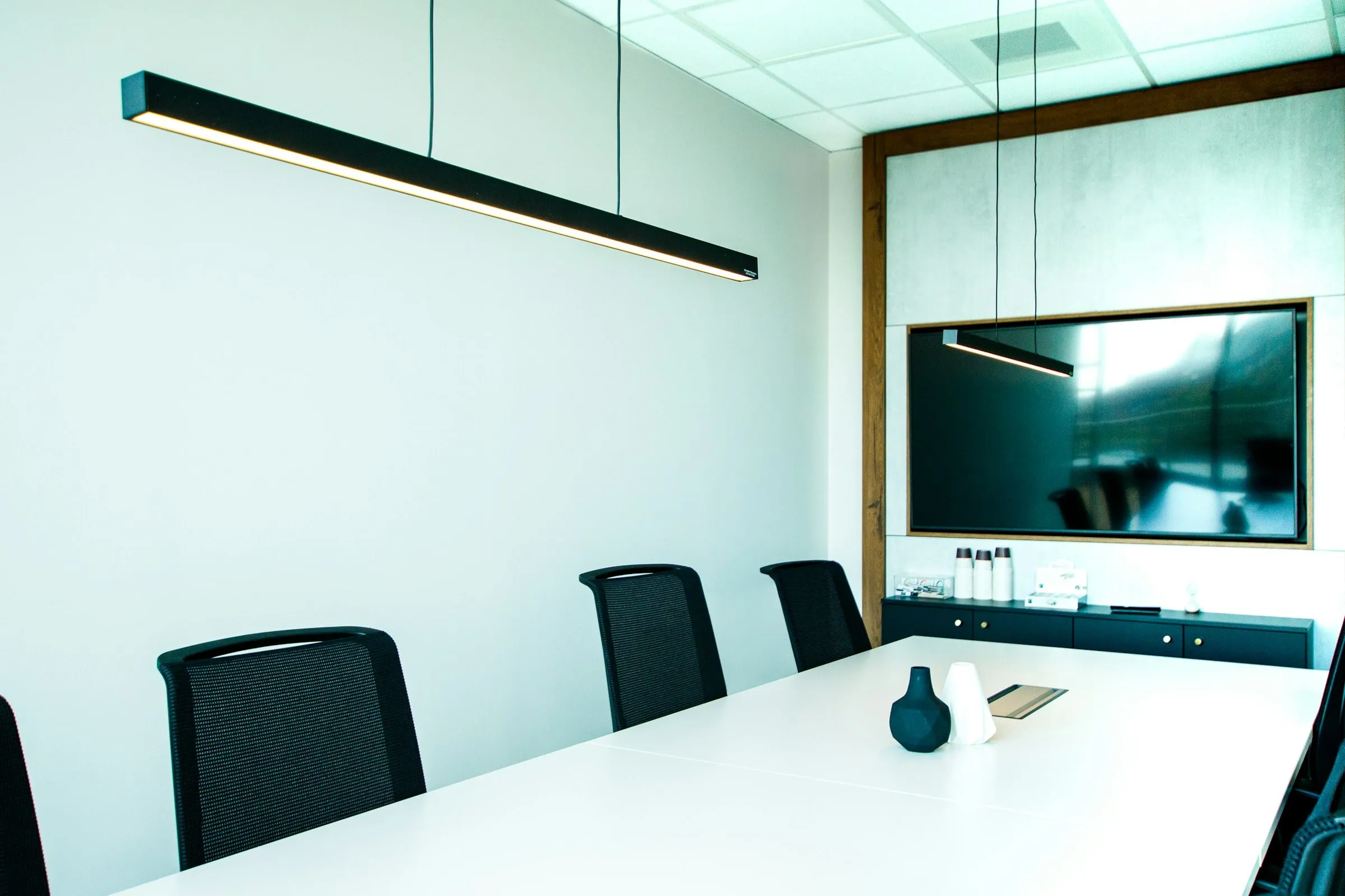 A bright conference room with a wall-mounted display above a long table