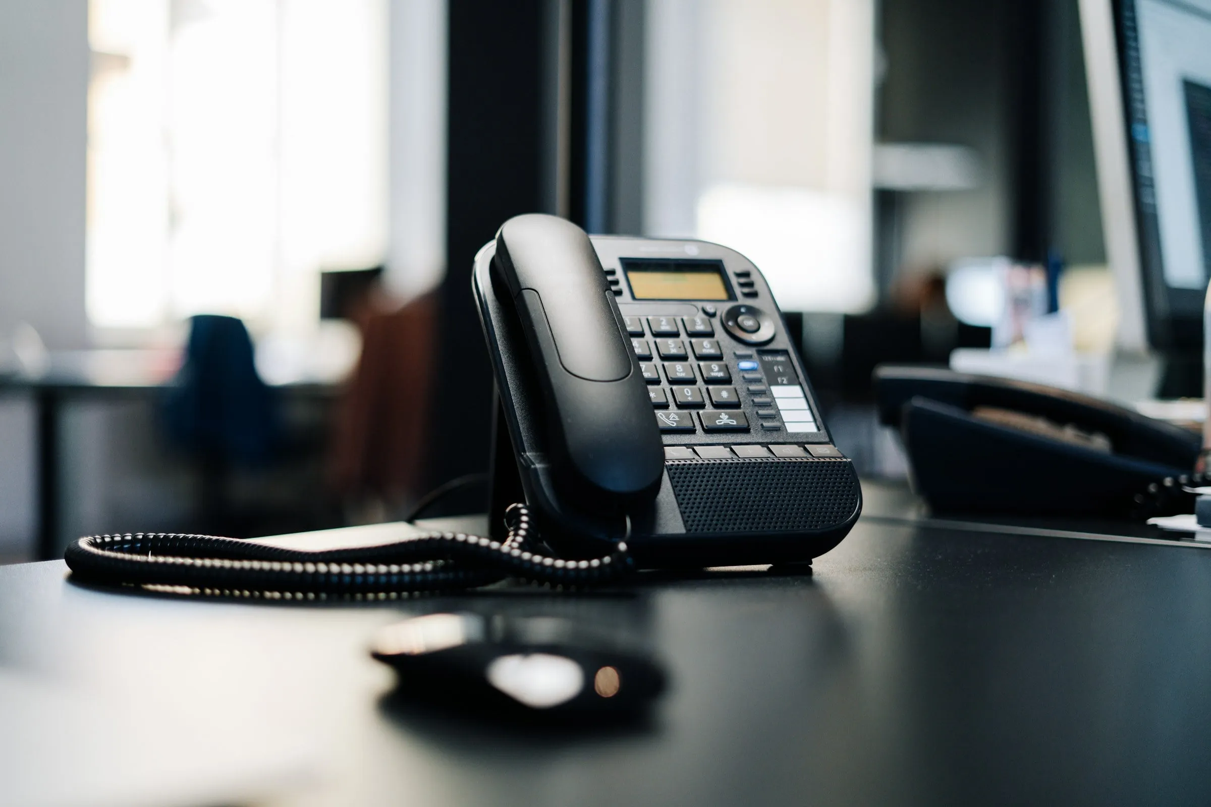 An IP desk phone on a desk in a bright office
