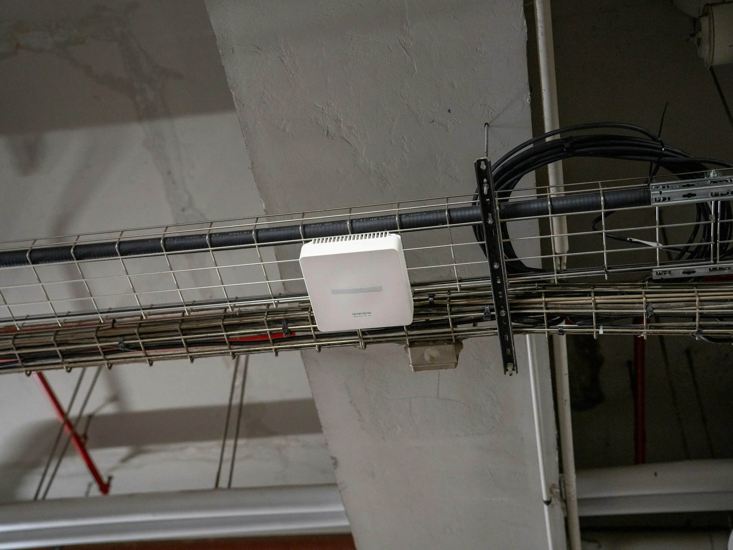 An enterprise Wi-Fi access point mounted on a ceiling cable tray